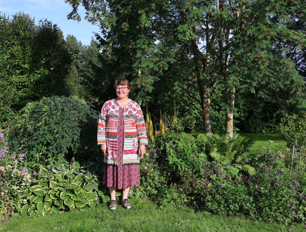 Virpi Syväjärven takana samalla istutusalueella kasvaa niin puita, pensaita kuin perennojakin.