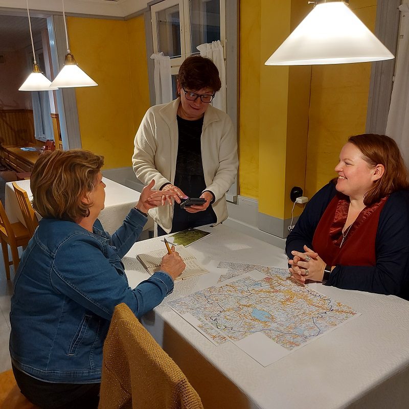 Arja Raatikainen (vas.) ja Terhi Mäkelä suunnittelevat reittejä Ruoka, juoma ja luonnontuotteet -teeman ympärille. Kouluttaja Arja Kortesluoma antaa hyviä vinkkejä. Hankkeen seuraavassa työpajassa paneudutaan myyntiin ja markkinointiin.