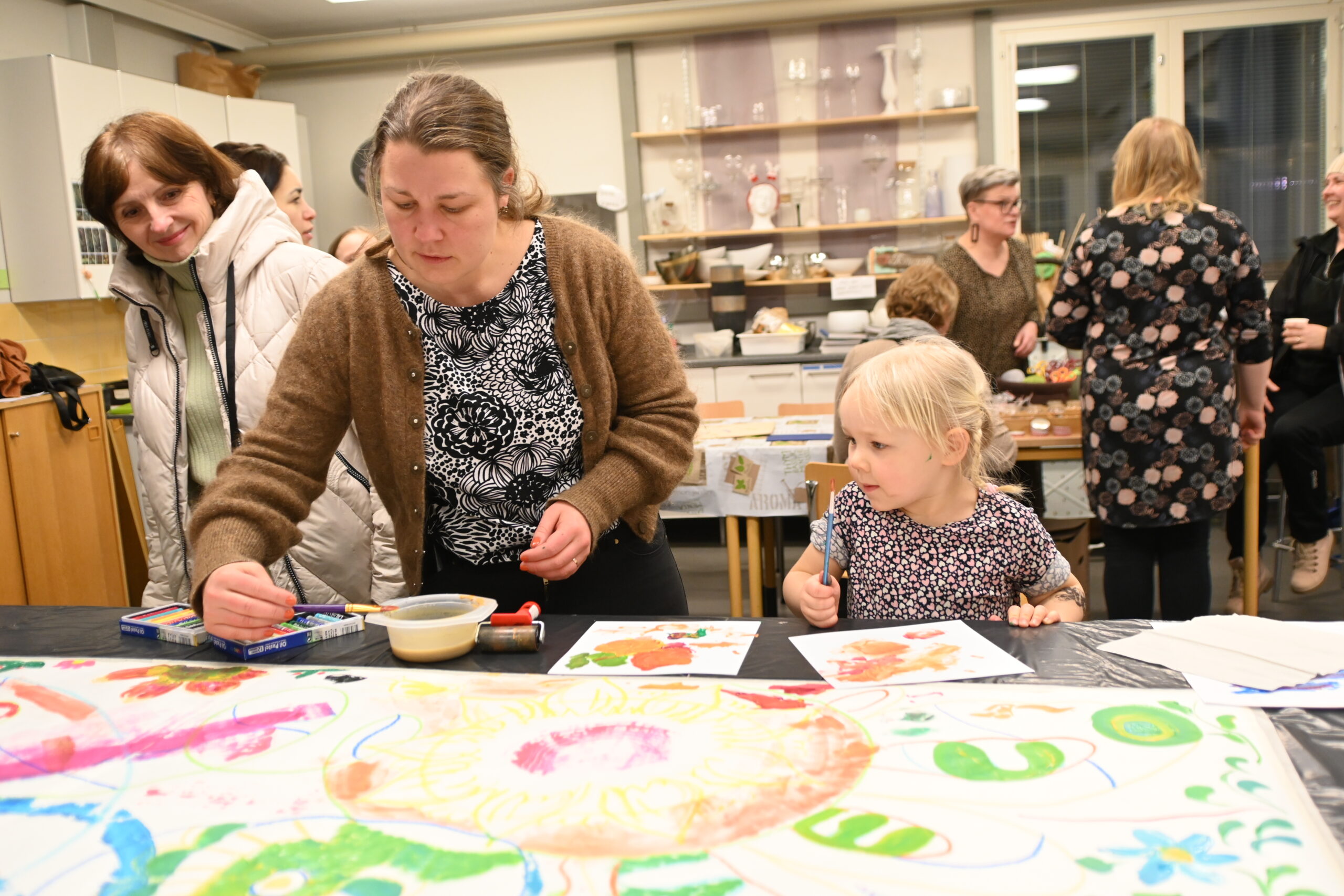 Illan aikana oli mahdollista osallistua yhteisen taideteoksen tekemiseen. Bea, 3, osallistui taidehetkeen äitinsä Inan kanssa. Useampaa kieltä puhuva perhe oli Alajärven mummolassa kyläilemässä.