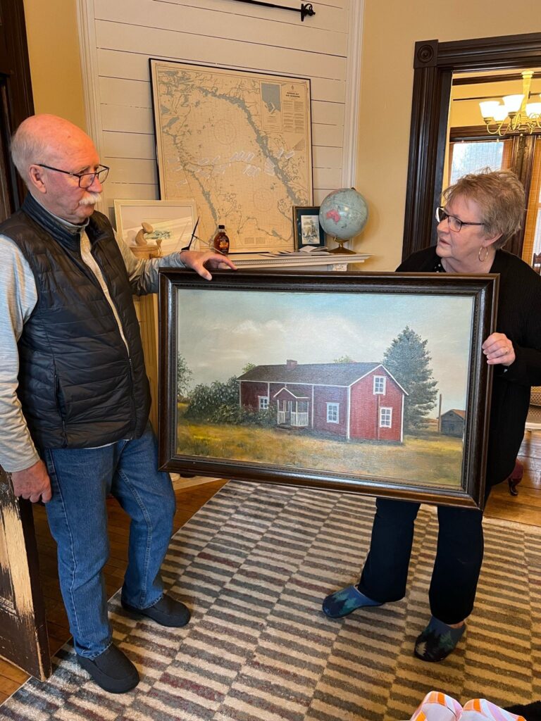 Sauli ja Cheryl Ahvenniemi esittelevät Harjun talosta maalattua taulua.