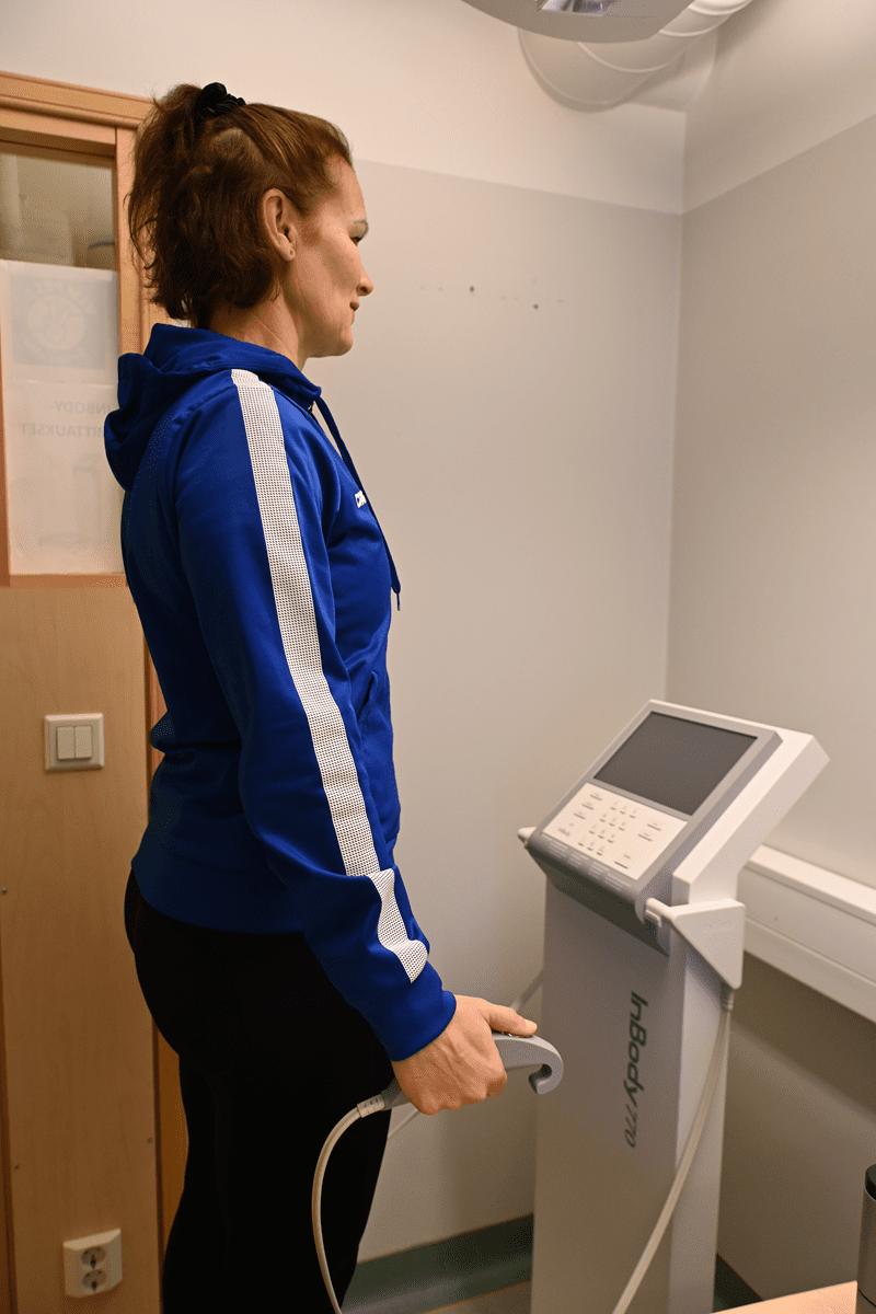 Karoliina Joohs näyttää, kuinka laitteessa kuuluu seistä. –Mittauspäivänä päälle on hyvä vetäistä rennot vaatteet, ohjeistaa Joohs.