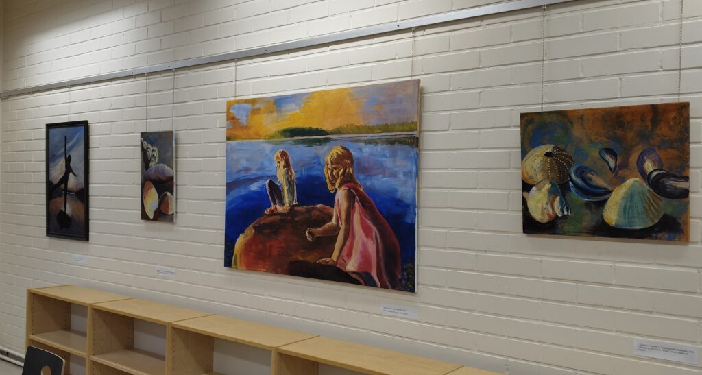 Kirjaston näyttelyssä on esillä iso työ Rauhan ranta, jossa ovat kuvattuina Marjaana Hinkan perheen lapset.