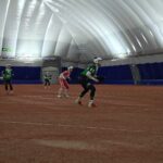 Alajärven Pallohalli tarjoaa kesäiset olosuhteet pesäpallo-otteluille myös talvella. Maria Lahti numerolla 5, sekä taustalla Elli Kangas ja Elise Lähdemäki yrittävät katkaista Jussien vaihtoyrityksen. Kuva: Piritta Kärnä.