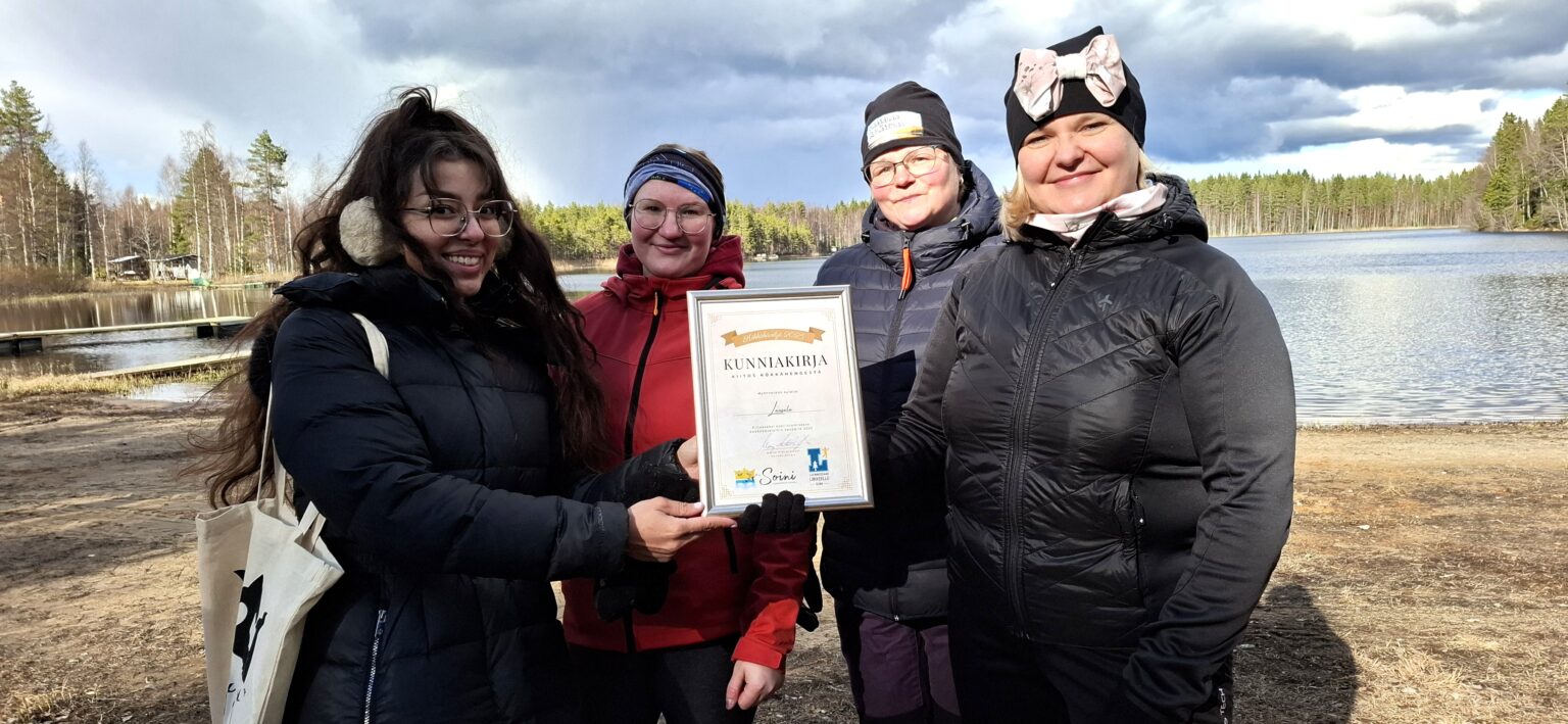 Cheyenne Järvinen (vasemmalla) luovutti kylälle kunniakirjan. Sen ottivat vastaan Julia Leppälä, Kirsi Niemenaho ja Maria Leppälä. Julia on uudehkoja soinilaisia, kotoisin Pohjois-Karjalan Rääkkylästä. Hän on myös nuorimman laasalalaisen, kohta 5 kk täyttävän Oliverin äiti.