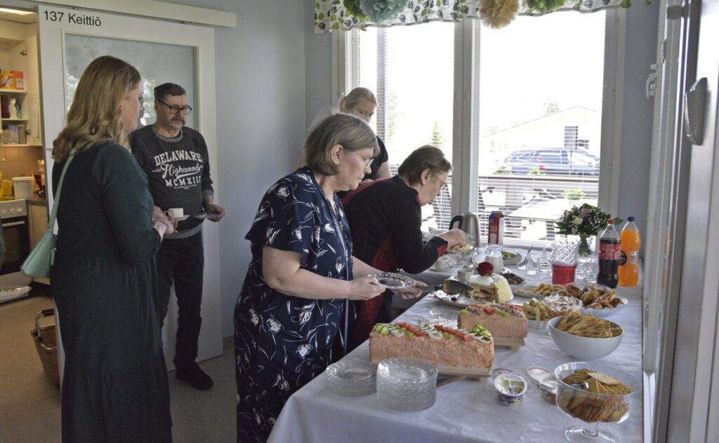 Seija Lehto leikkaa syntymäpäiväkakkua ja Kirsi Takala voileipäkakkua. Maistuvat tarjoilut olivat Joelinkodin keittiöhenkilökunnan käsialaa.