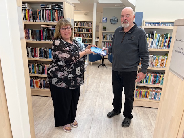 Tommi Borg luovutti Evijärven kirjastolle uuden kirjansa. Kirjastonjohtaja Merle Kupila otti lahjoituksen tyytyväisenä vastaan.