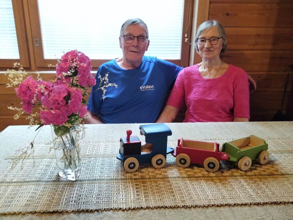 Pöydällä on alinna Railin kutoma pellavaliina, jonka materiaali on kasvatettu itse siemenestä asti, sen päällä itse kudottu kaislaliina. Reiman aikanaan tekemässä puujunassa on hyödynnetty tarhakoppien tuotannosta yli jääneitä puunpaloja.