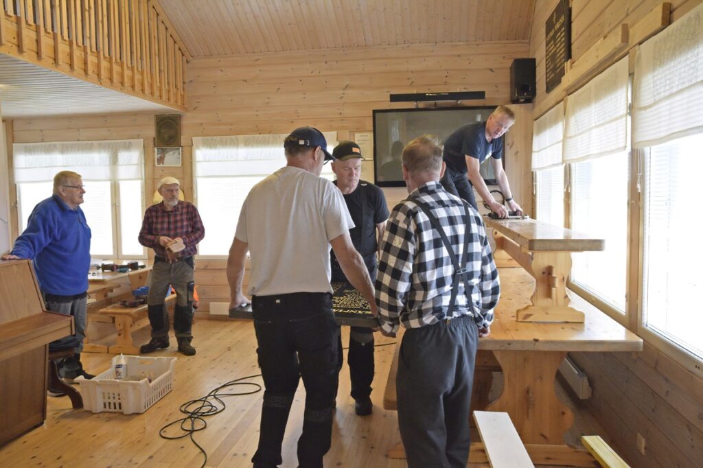 Isompi laatta nostettiin ensin pöydälle, siitä penkille ja lopulta seinälle tukirakenteiden päälle. Laattojen taakse laitettiin tukilaudat, jonka läpi laatat pultattiin seinään kiinni.