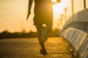Silhouette of a young fitness man running on sunrise