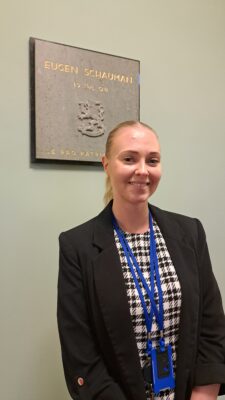 Emma-Lotta Annola Valtioneuvoston linnan tunnetuimmassa portaikossa. Taustalla on laatta vuonna 1904 tapahtuneesta surmatyöstä. Tällä paikalla Eugen Schauman ampui kenraalikuvernööri Bobrikovin, joka pyrki venäläistämään Suomea.