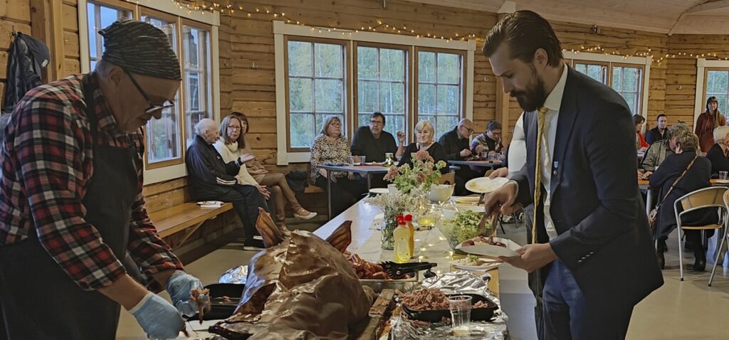 Kunnanjohtaja Sam Leijonanmieli (oik.) iloitsi kotikylänsä saamasta huomionosoituksesta ja kiitti aktiivien tekemästä runsaasta talkootyöstä. Kannonkoskelainen Simo Mäkelä toimitti sian ja hoiti myös sen tarjoilun. Kuva: Eija Pippola. 