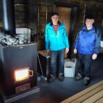 Jukka Kuusela ja Hannu Soisalo kuuluvat saunan lämmittäjäkaartiin. Puolentoista tunnin lämmitysaika uudessa saunassa on ollut iloinen yllätys, pidempään oli varauduttu.