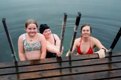 Elli ja Salla Laukkonen sekä Sarita Ruuhinen virkistäytymässä järvessä. Yhdeksänvuotiaalle Ellille tämä on ensimmäinen kylmävesiuintikerta!