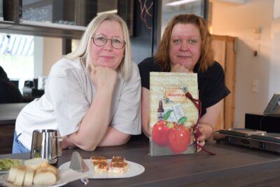 Jenna Heikkilä (vas.) ja Jutta Tuomela ovat kahvilaansa suunnitellessaan usein katselleet äitinsä kokoamaa reseptikirjaa: nyt se on taas kovassa käytössä.