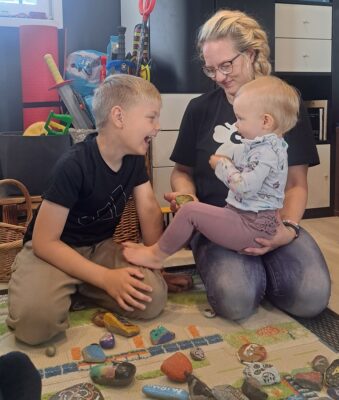 Julius ja Piia-äidin sylissä oleva Justiina tutkivat innostuneesti kiviä, joita kotiin onkin kertynyt melkoinen määrä.