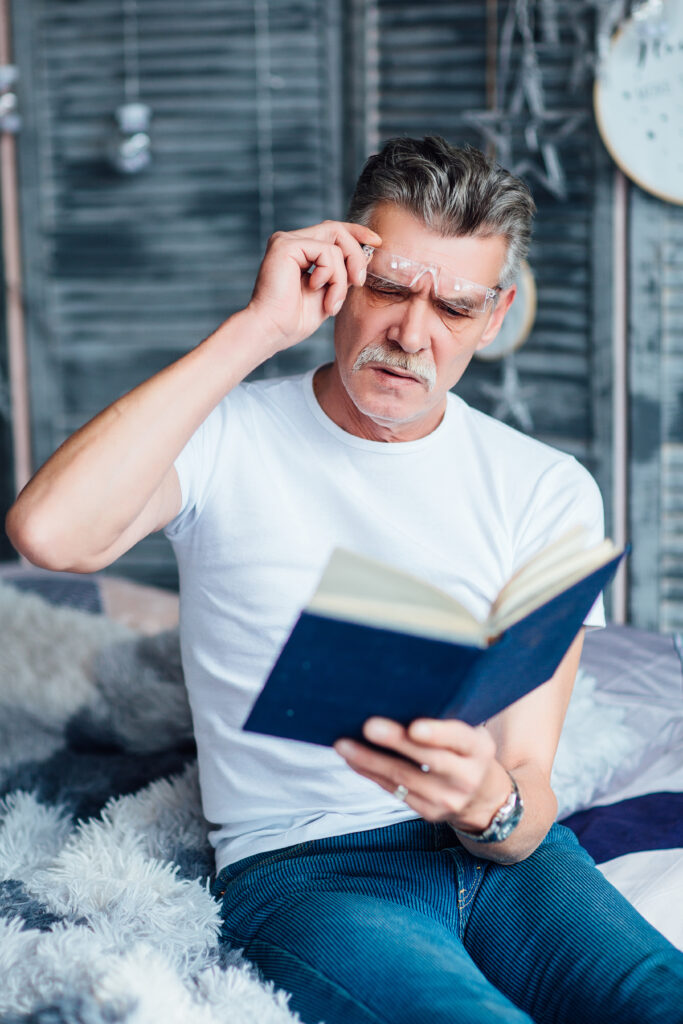 Time for reding! Eldery bearded man with his favourite book, sitting on sofa!
