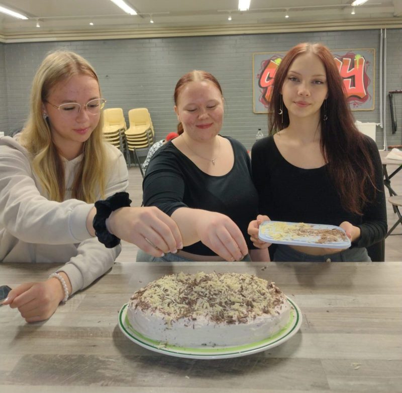 Liisi Harju (vas.), Ida Pakulla ja Mira Osmonen viimeistelivät Nuorisotalolla kakkua iltaa varten. Kuva: Anu Peltokangas.